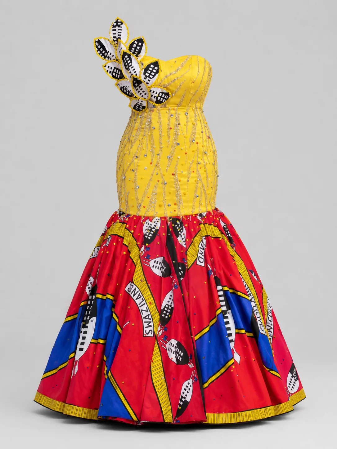 Strapless gown with a yellow beaded bodice, shoulder accent and a red, blue and yellow printed flared skirt